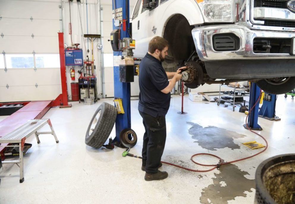 Mechanic inspecting a truck's brakes in a garage.